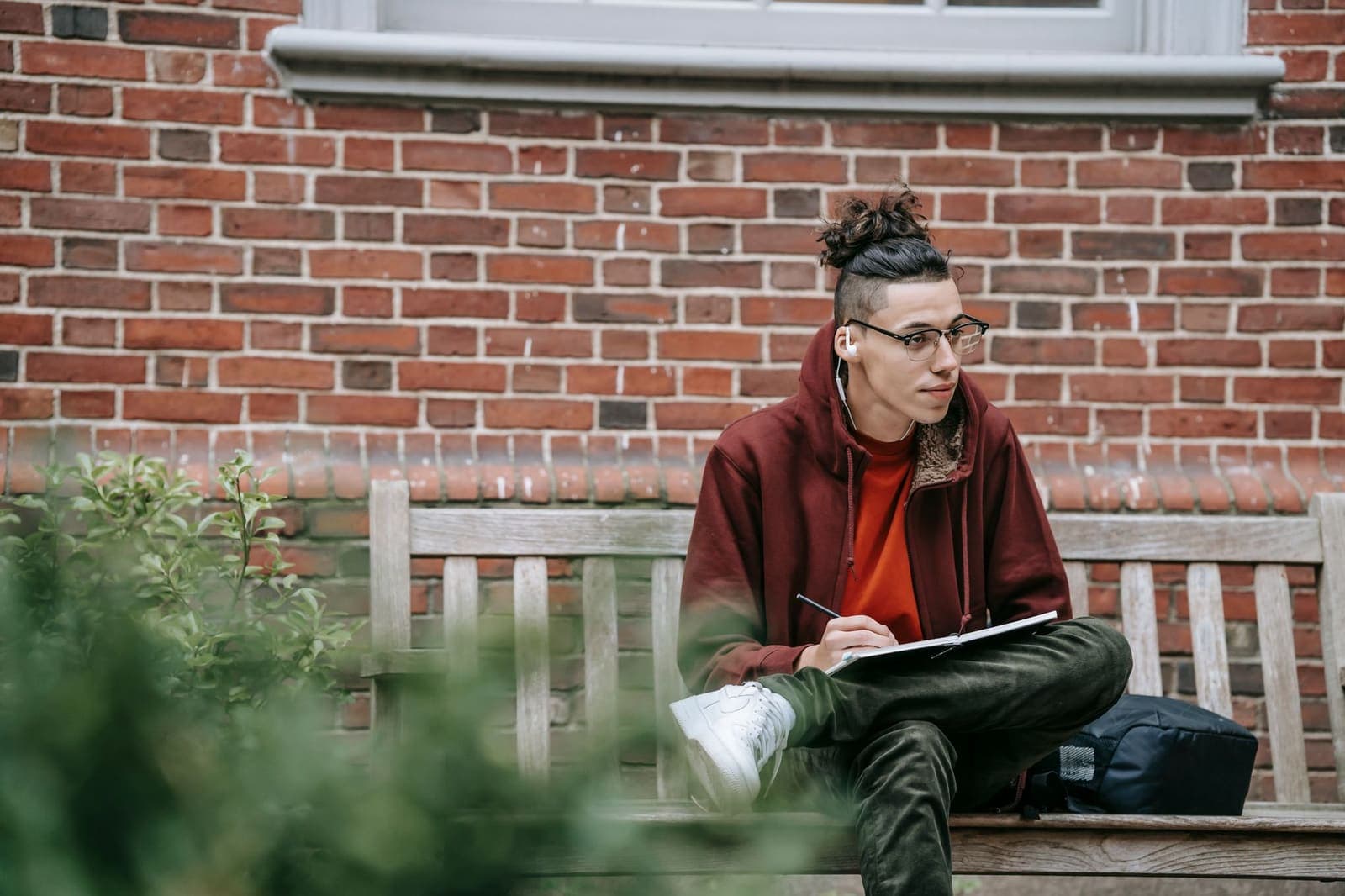 A child doing homework on a shop step, notebook on knees.