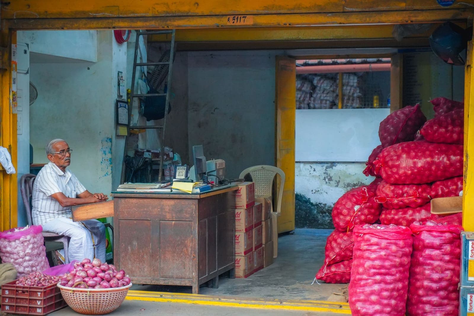 A shopkeeper raising a metal shutter with one shoulder.