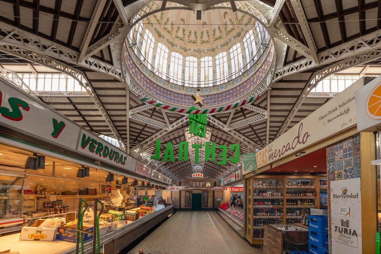A market lane seen end to end, light on the upper wall only.